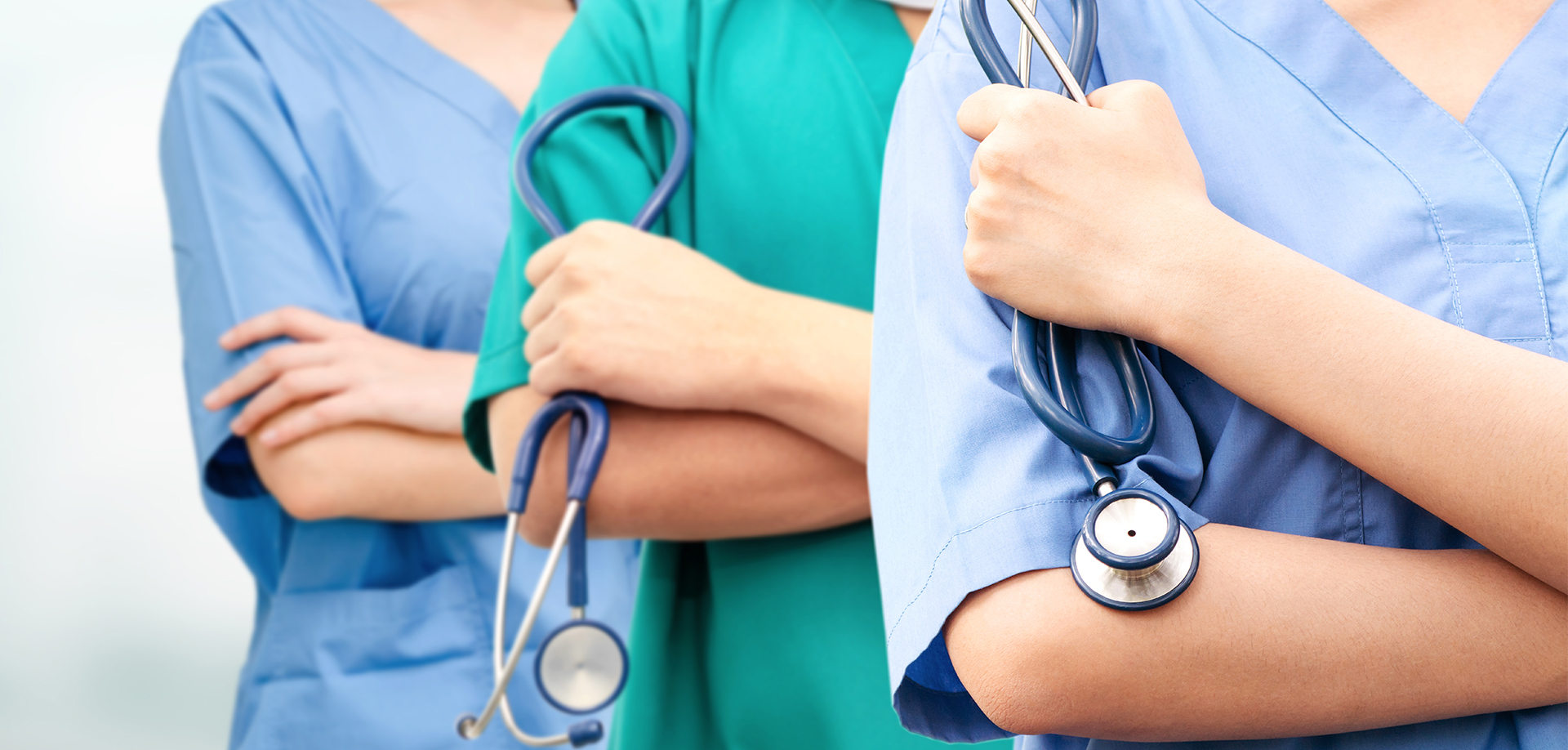 Three doctors standing next to each other with two of them holding a stethoscope